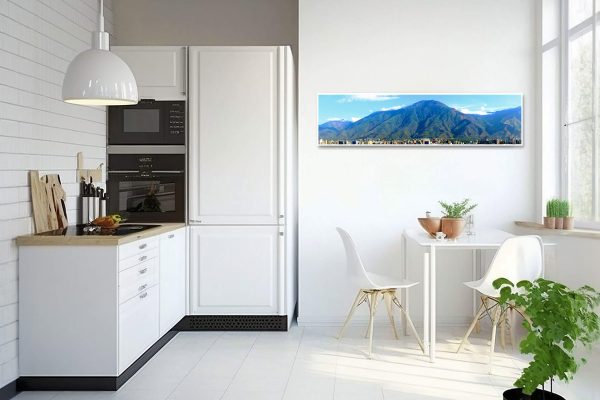 Guardian Ávila panoramic fine art canvas print displayed on the wall of a modern white kitchen with a small dining area.